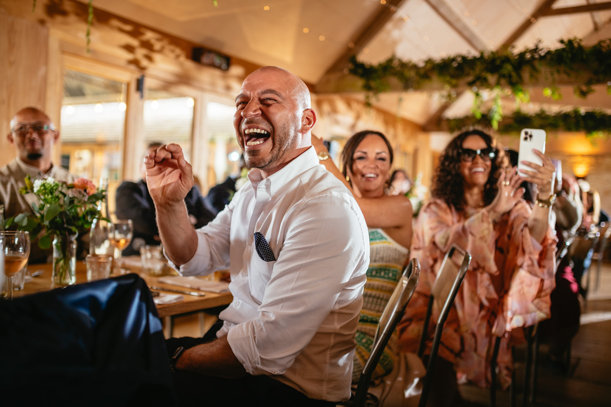 A guest laughing during a speech at a wedding in south wales captured by a professional wedding photographer