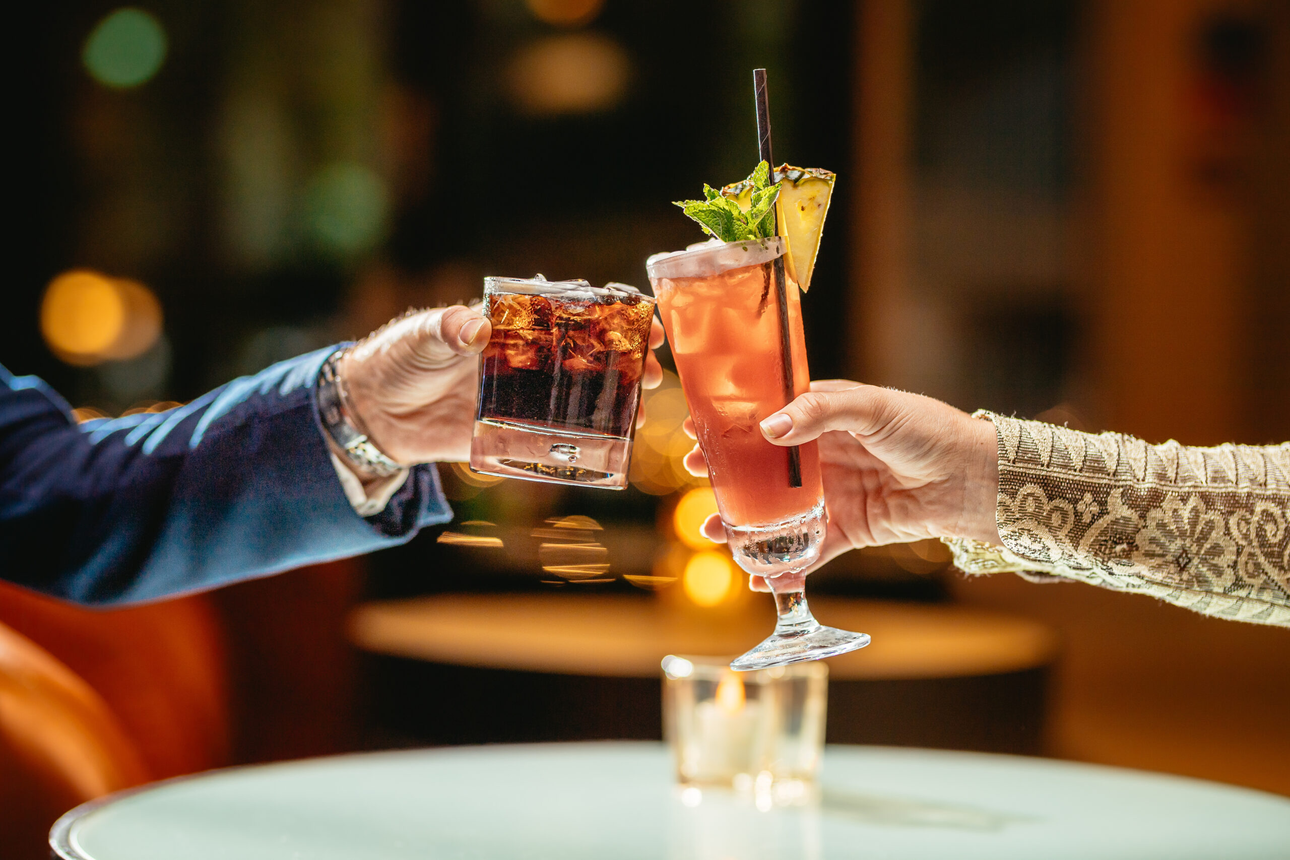 two drinks touching, one cocktail, one coke with ice