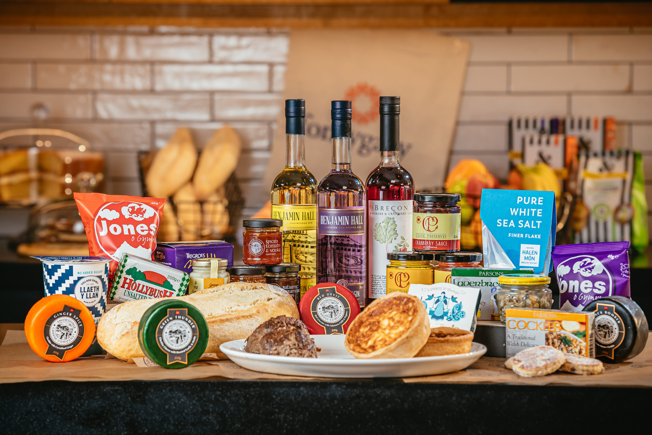 a selcttion of produce including cheese, bread, pies and jars
